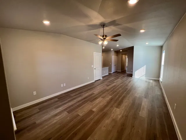 an empty room with wooden floor and ceiling fan