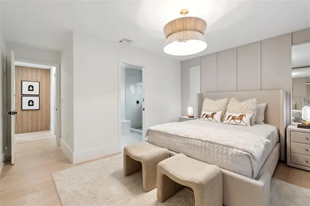 a large white bed sitting in a room next to a lamp and a large window