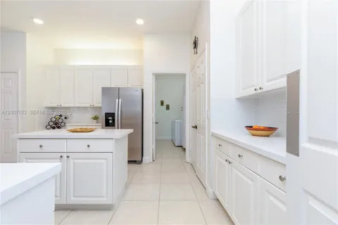a kitchen with white cabinets and refrigerator