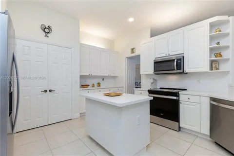 a kitchen with stainless steel appliances granite countertop a stove top oven a sink and dishwasher with white cabinets