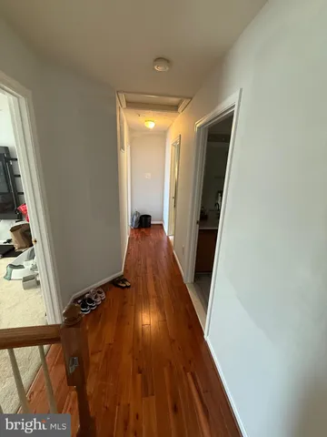 a view of a hallway to a bedroom with wooden floor and stairs