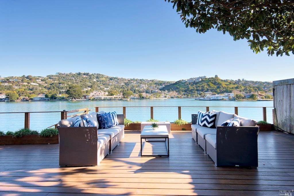 an outdoor seating with wooden floor and lake view