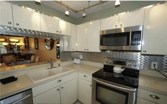 a kitchen with stainless steel appliances wooden cabinets a stove a sink and a microwave