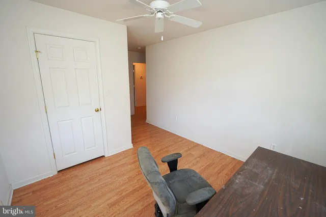 a view of a bedroom with wooden floor and a ceiling fan