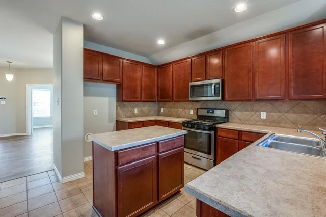 a kitchen with stainless steel appliances granite countertop wooden cabinets a stove top oven a sink and dishwasher