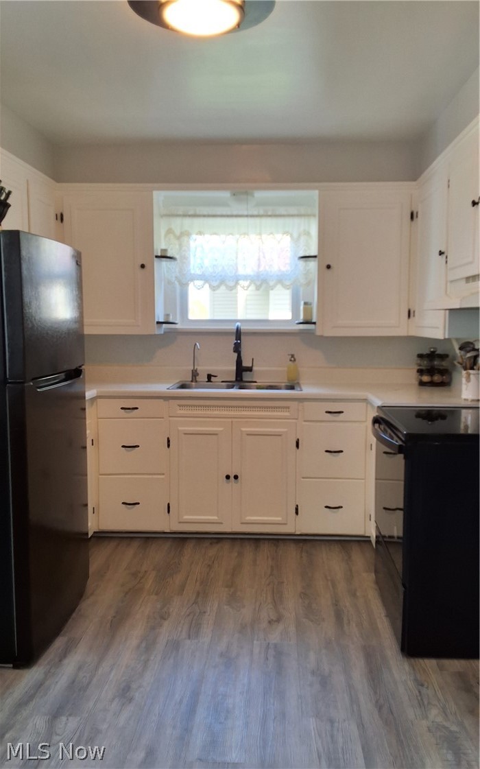 236 Bowland Road Mansfield, OH 44907 - Photo 13 of 34 Kitchen featuring a window above the sink, white cabinetry with black hardware, light-toned countertops, and wood-finish flooring