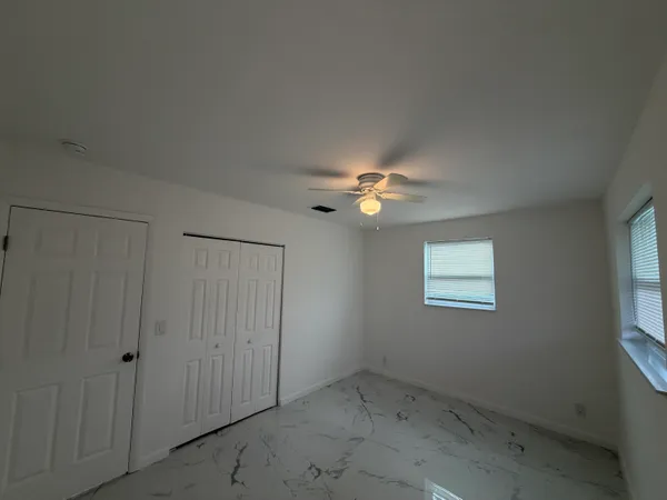 an empty room with windows and fan
