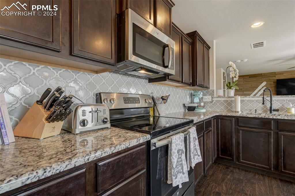11305 Avena Road Peyton, CO 80831 - Photo 12 of 47 a kitchen with stainless steel appliances granite countertop a sink stove and microwave