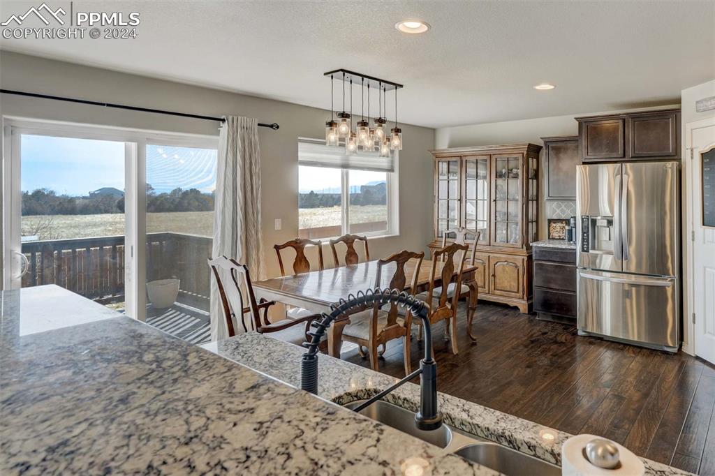 11305 Avena Road Peyton, CO 80831 - Photo 16 of 47 a dining room with furniture a chandelier and wooden floor
