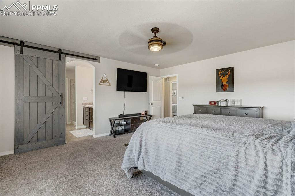 11305 Avena Road Peyton, CO 80831 - Photo 21 of 47 a spacious bedroom with a bed and a flat screen tv