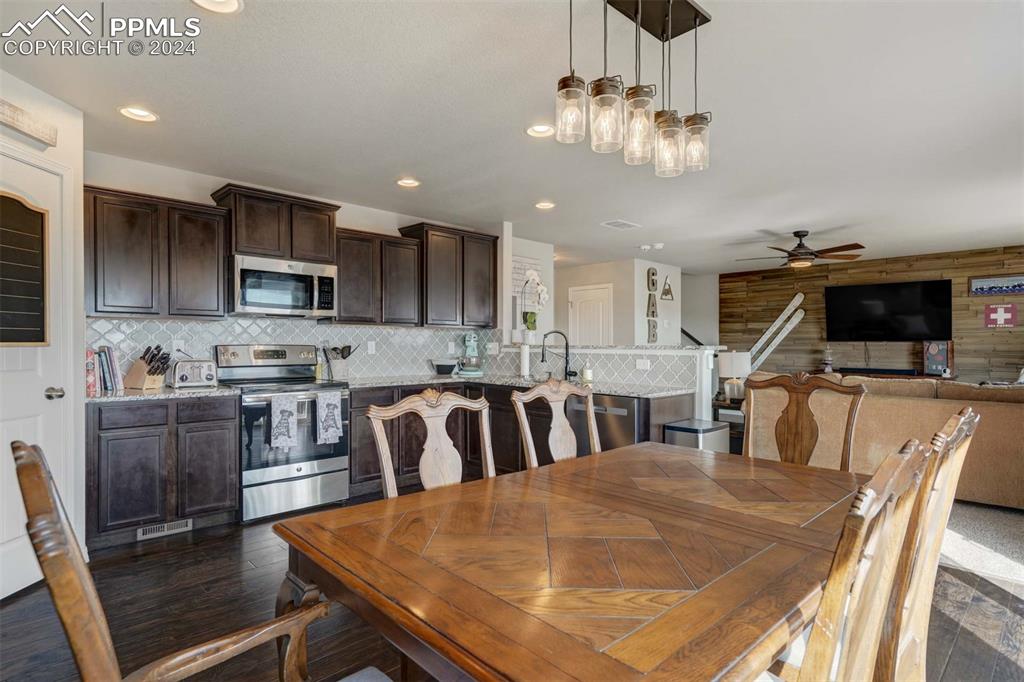 11305 Avena Road Peyton, CO 80831 - Photo 10 of 47 a kitchen with stainless steel appliances granite countertop a stove top oven a sink a dining table and chairs