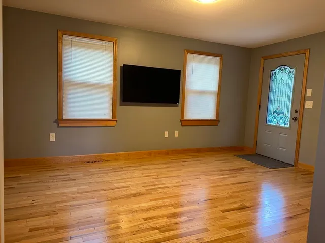 a view of an empty room with window and wooden floor