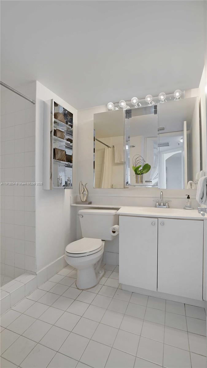 1621 Bay Road, Unit 606 Miami Beach, FL 33139 - Photo 17 of 32 a bathroom with a toilet a sink a mirror and vanity