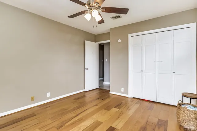 an empty room with wooden floor fan and windows
