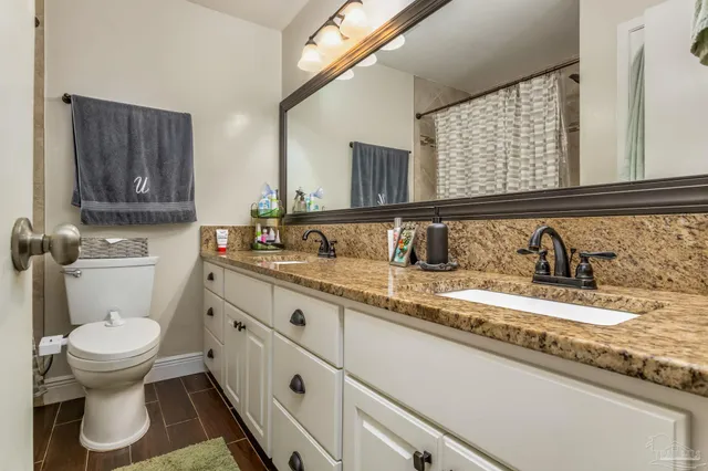 a bathroom with a granite countertop sink and a toilet