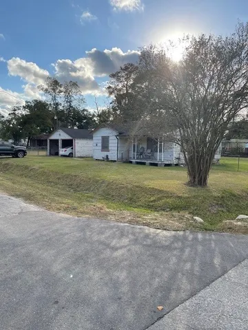 a view of a house with a yard and large trees