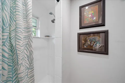 a picture of a bathroom with a shower and a painting on the wall