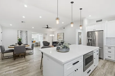 a kitchen with stainless steel appliances kitchen island granite countertop a table chairs and a refrigerator
