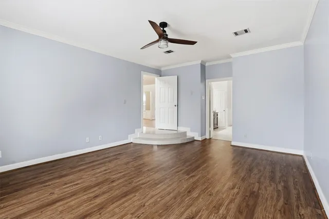 a view of empty room with wooden floor and fan