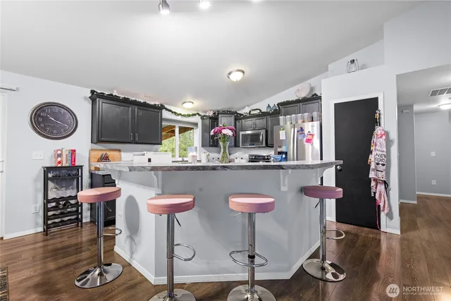 a kitchen with stainless steel appliances granite countertop a table chairs and a refrigerator