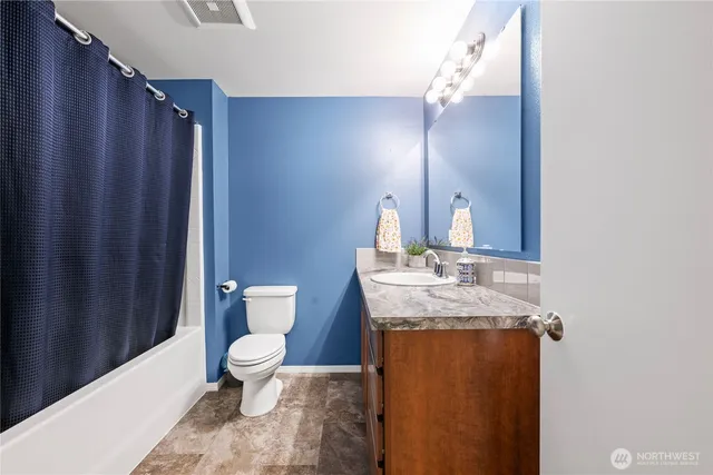 a bathroom with a granite countertop sink toilet and mirror