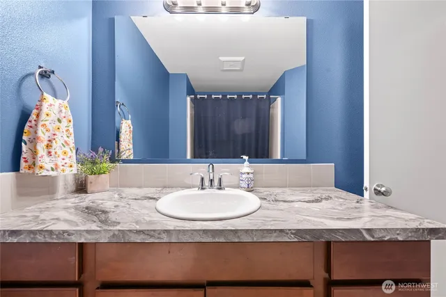 a bathroom with a granite countertop sink and a mirror