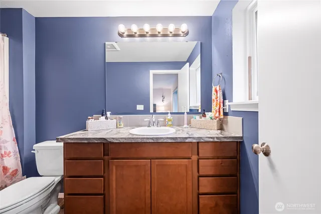 a bathroom with a granite countertop sink a toilet and a mirror