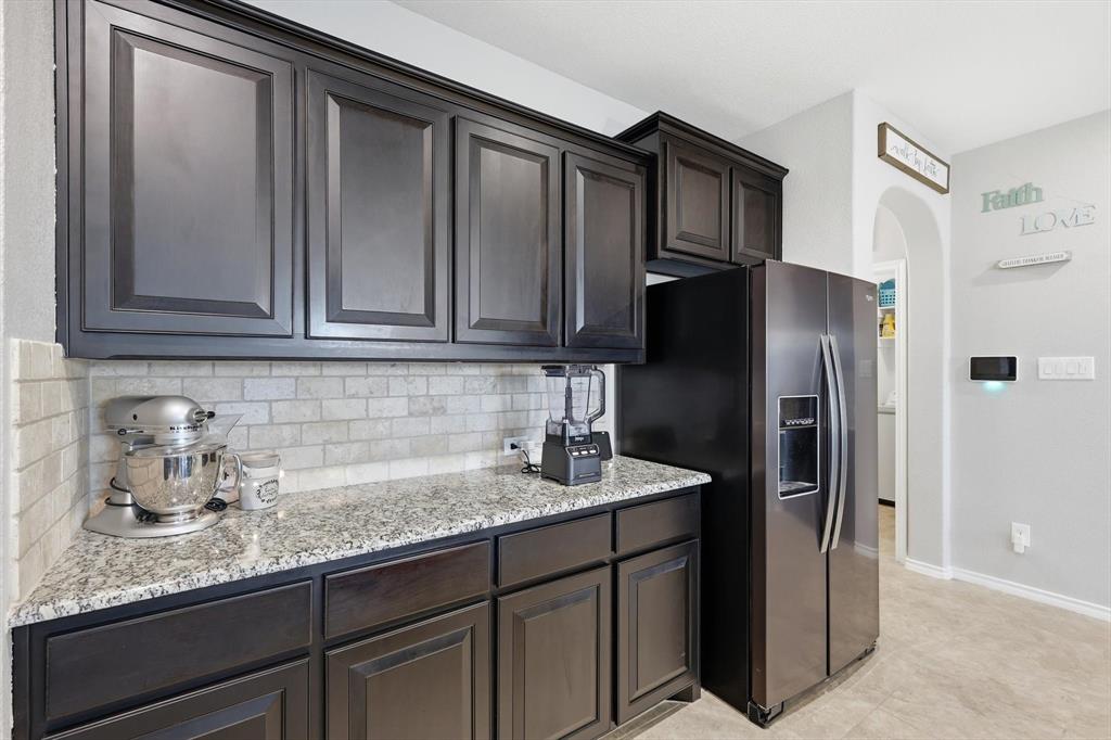 11500 Starlight Ranch Fort Worth, TX 76052 - Photo 17 of 40 Kitchen featuring dark wood cabinetry, light-colored granite countertops, and a tiled backsplash