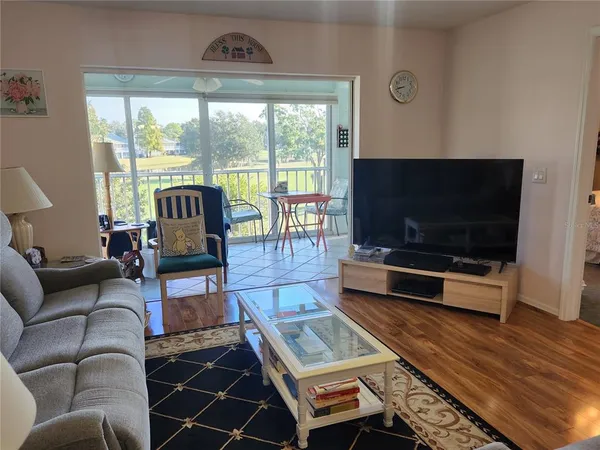 a living room with furniture a flat screen tv and a floor to ceiling window