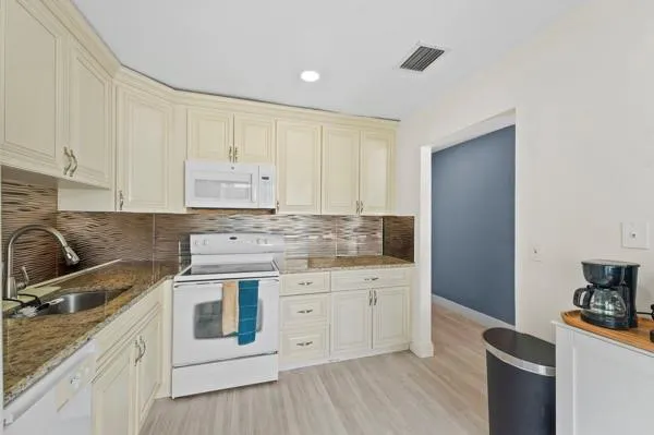a kitchen with granite countertop white cabinets and white appliances