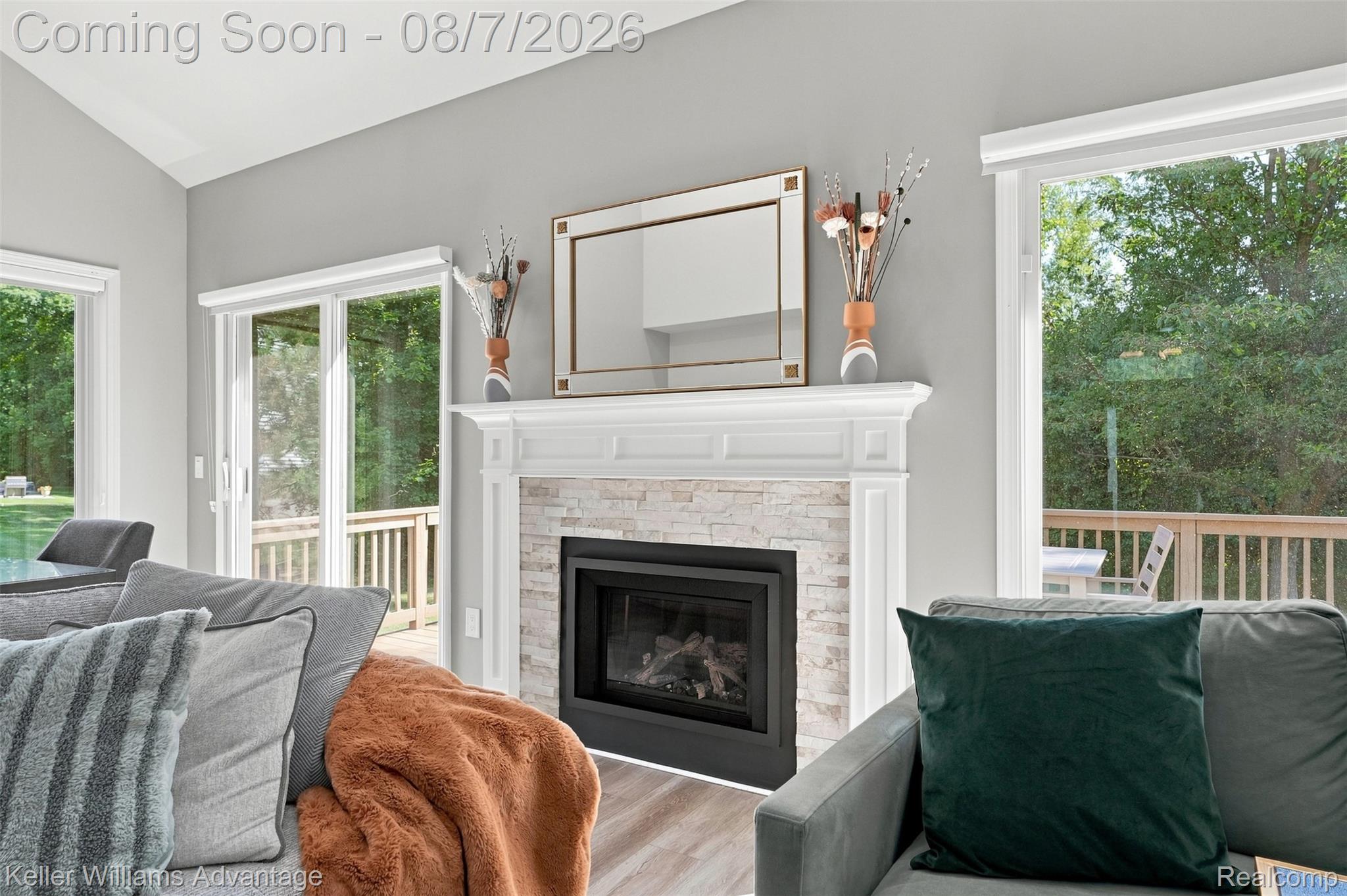 5325 Simpson Lake Road West Bloomfield, MI 48323 - Photo 7 of 43 Vaulted ceiling, gas fireplace with stone surround, white mantel, sliding glass doors, and wood-finish flooring