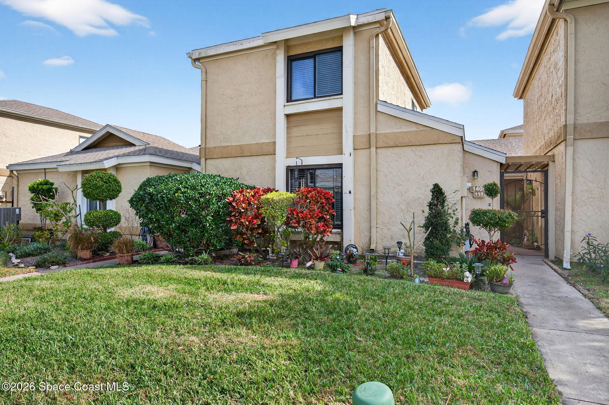 1400 Sheafe Avenue Northeast, Unit 110 Palm Bay, FL 32905 - Photo 2 of 35 a front view of a house with a yard and potted plants