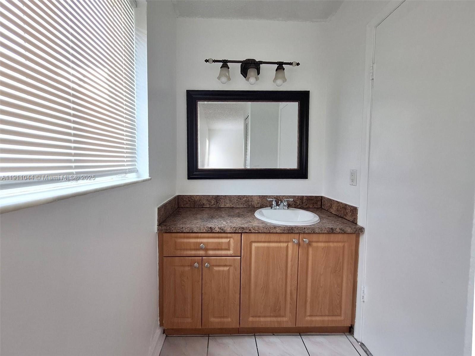 2011 Bay Drive, Unit 3 Miami Beach, FL 33141 - Photo 8 of 14 a bathroom with a granite countertop sink and a mirror