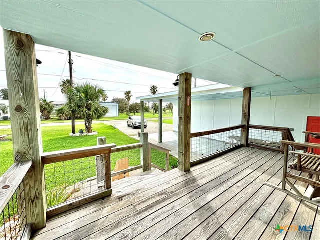a view of a house with wooden floor and trees in the background
