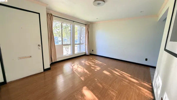 a view of an empty room with wooden floor and a window