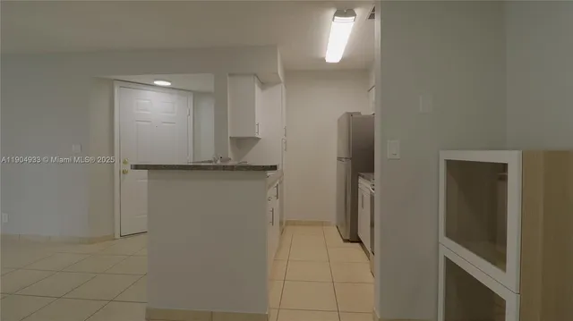 a view of a refrigerator in kitchen and an empty room