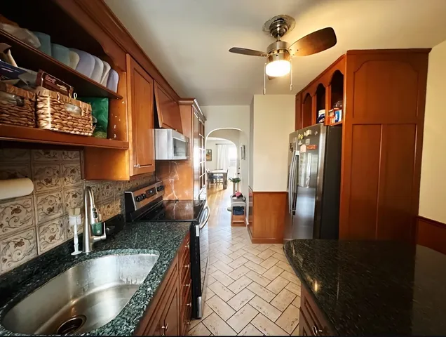 a kitchen with stainless steel appliances granite countertop a sink a refrigerator and a stove