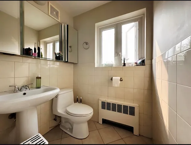 a bathroom with a toilet a sink a mirror a window and vanity