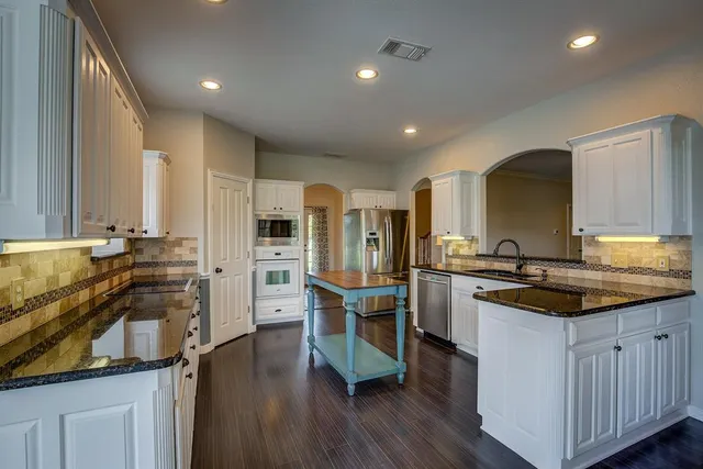 a kitchen with appliances a sink cabinets and wooden floor