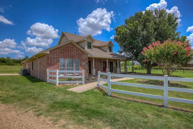 a view of a house with a yard potted plants and large tree