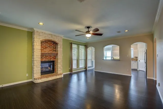 an empty room with wooden floor fireplace and windows