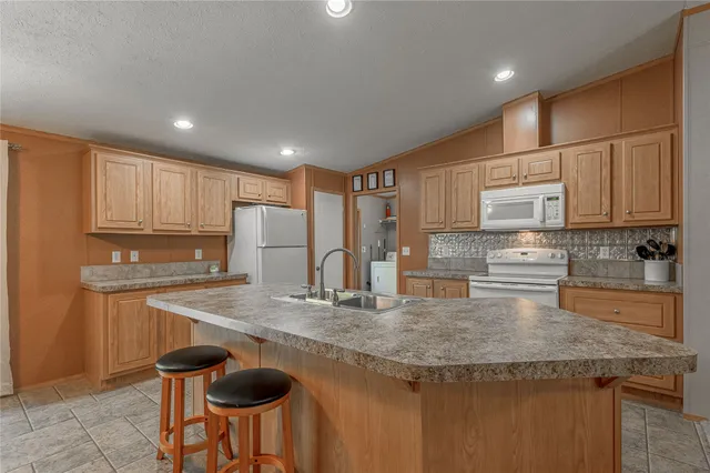 a kitchen with granite countertop kitchen island stainless steel appliances a sink stove and refrigerator