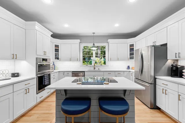 a kitchen with stainless steel appliances a sink a stove a refrigerator cabinets and wooden floor