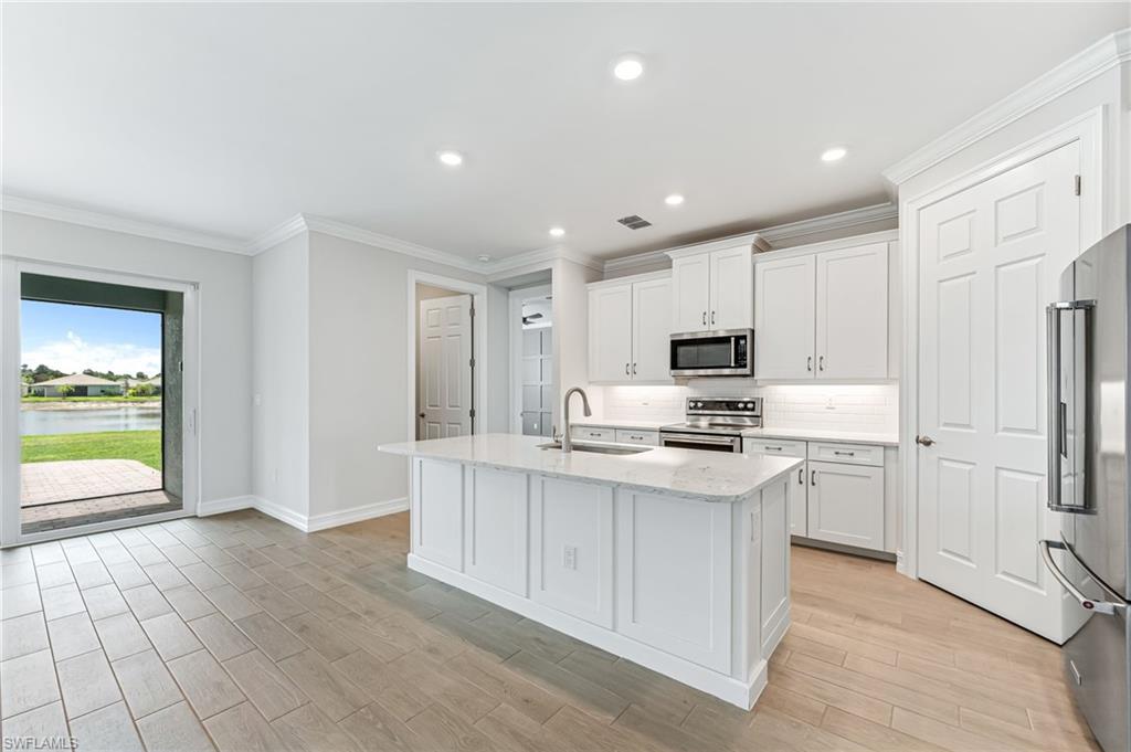 475 Polihale Way Naples, FL 34114 - Photo 9 of 27 a kitchen with stainless steel appliances granite countertop a refrigerator oven a sink dishwasher and white cabinets with wooden floor