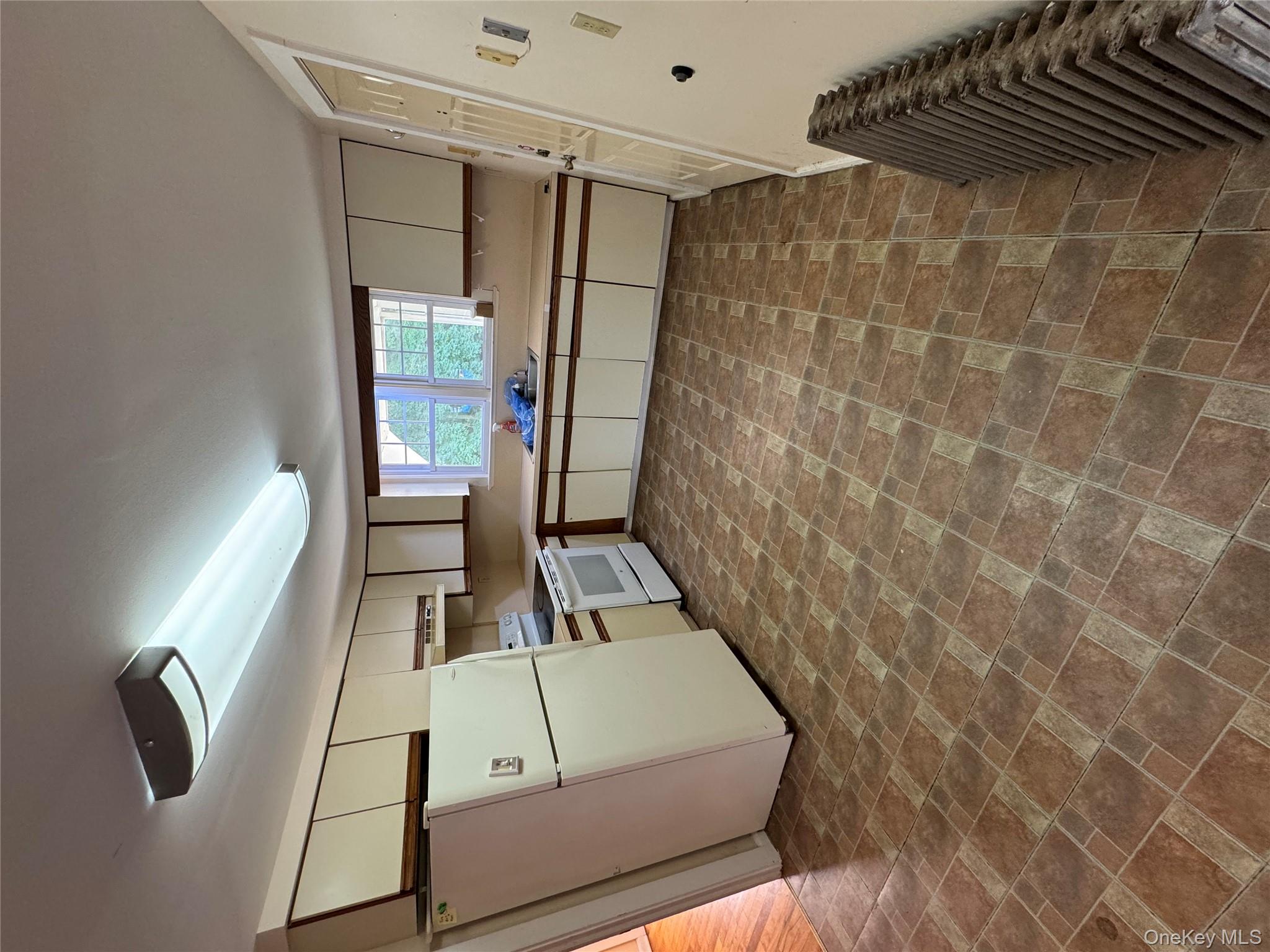 560 State Rte 44 55, Unit D Highland, NY 12528 - Photo 5 of 13 Kitchen with fridge, stove, light countertops, radiator, and brick patterned floors