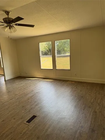 an empty room with a wooden floor and windows