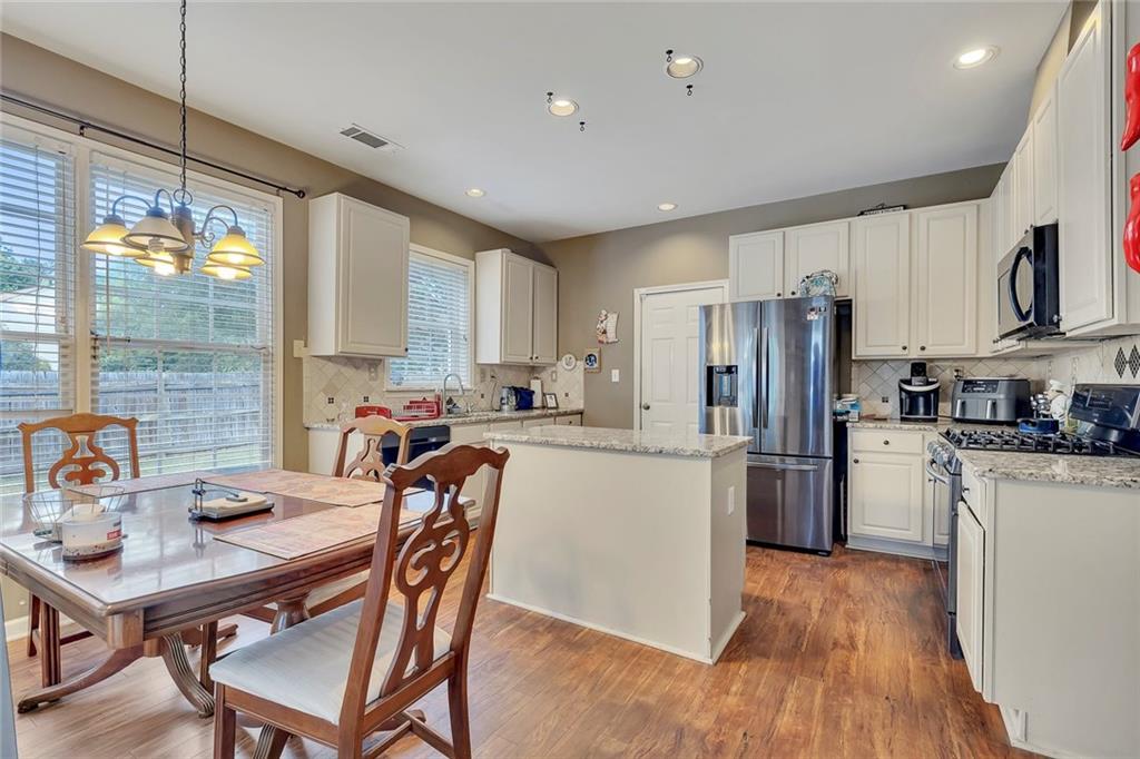 785 Hedgewick Trail Alpharetta, GA 30022 - Photo 13 of 32 a kitchen with refrigerator cabinets dining table and chairs