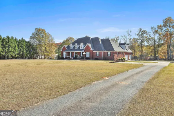 a view of a big house with a big yard and large trees