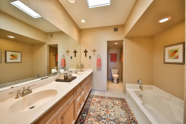 a spacious bathroom with a double vanity sink a mirror and a bathtub