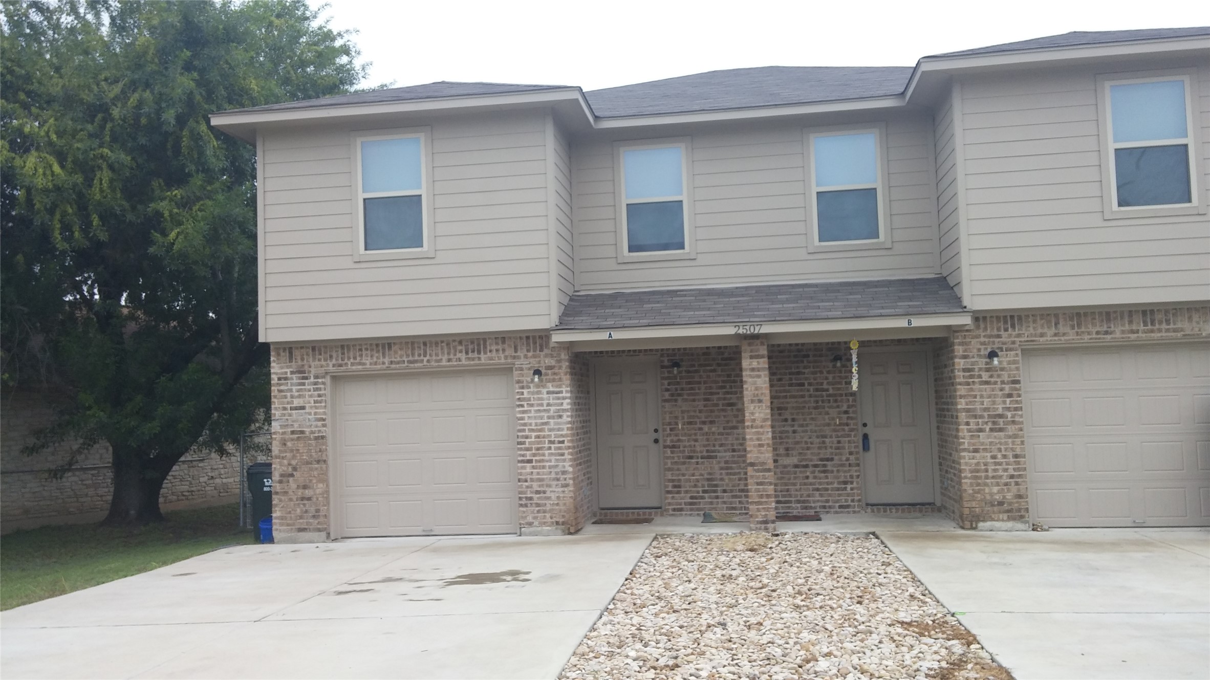 2507 Oak Lane, Unit A Georgetown, TX 78628 - Photo 1 of 11 A duplex property presenting a functional layout, featuring individual garages and welcoming front entryways.